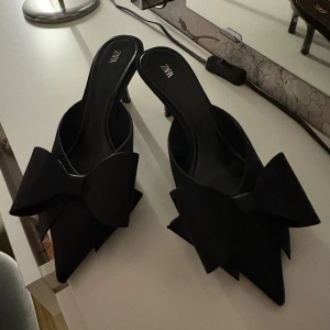Svarta klackar - Svarta klackar med rosett från Zara andvänd endast 2 gånger. Jätte jätte fina klackar. Kostar 500 kr nya