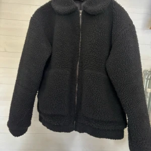 Svart teddyjacka från Tindra - Mysig svart teddyjacka från Tindra med dragkedja framtill och två fickor. Nästan aldrig använd så mycket bra skick. 