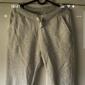Ljusgrå mjukisbyxor med snörning M - Ljusgrå mjukisbyxor i bomullsmix med ribbad midja och snörning. Byxorna har två sidofickor fram och två bakfickor med broderad detalj.  Tyvärr har dom blivit lite noppriga (se bild) och har klippt bort lappen