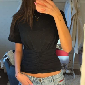 Svart topp cider - Säljer en svart topp från cider med korta ärmar och snygg rynkdetalj över magen. Verkligen såå snygg!💕