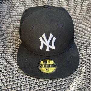Svart New Era Yankees keps 59FIFTY - En snygg svart keps från new era med New York Yankees på fram sidan. Perfekt för dig som gillar streetstyle och sport. Kepsen är i bra skick men ändå rätt så använd. Hör av dig vi minsta fundering!