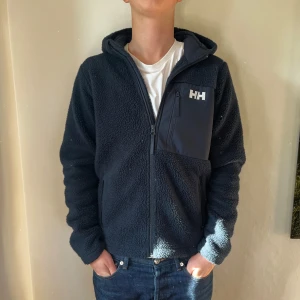 Mörkblå teddyjacka från Helly Hansen - Mörkblå teddyjacka med huva från Helly Hansen. Jackan är i barnstorlek men passar XS. Nypris - 1000kr. Mitt pris - 599kr.