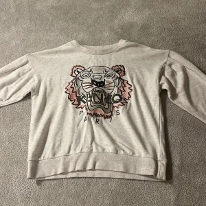 Vit Kenzo sweatshirt - Säljer en vit sweatshirt från Kenzo med  tigerbrodyr och Paris-tryck framtill. Tröjan har rund hals, långa ärmar. Säljer för den är för liten, bara använt ca 2-4 gånger 