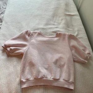 Ljusrosa sweatshirt från Gina Tricot - Superfin ljusrosa sweatshirt från Gina Tricot med puffiga korta ärmar och ribbade muddar. Tröjan är i mjuk bomullsmix och har en klassisk rund halsringning. Perfekt för dig som gillar en söt och enkel stil. Helt oanvänd och har inga märken.