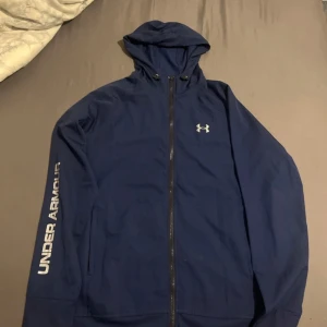 Blå vindjacka från Under Armour - Under armour vindjacka som jag inte använder. Det är storlek L men den passar bättre M