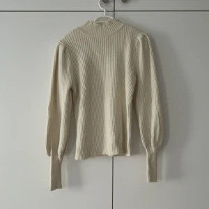 Beige ribbad stickad tröja från ONLY - Säljer en beige ribbad stickad tröja från ONLY i storlek S. Tröjan har långärmade puffärmar, hög hals och är i ett mjukt material som passar perfekt till höst och vinter. Enkel att styla med både jeans och kjol. Pris 199kr, ordinarie 399kr