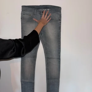 Grå skinny jeans från &Denim H&M - Snygga grå skinny jeans från &Denim by H&M med låg midja. Jeansen har klassisk femficksdesign, smal passform och är tillverkade i stretchig denim för en bekväm känsla. Perfekta för dig som gillar en tight siluett och stilren look.