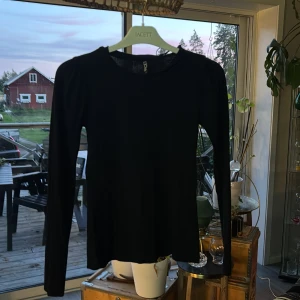 Svart ribbad långärmad topp Pieces - Svart långärmad topp från Pieces i storlek XS. Modellen har rund halsringning, lätt puff vid axlarna och är ribbad i materialet för en snygg struktur. Perfekt att styla med jeans eller kjol för en clean look.