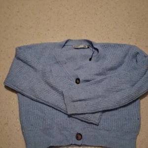 Ljusblå kofta från 157 med knappar - Superfin ljusblå kofta från 157 med tre stora knappar framtill. Koftan är stickad och har en v-ringad halsringning samt långa ärmar. Perfekt för lager på lager och ger en chill vibe till din outfit.