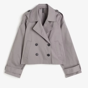 Kort trenchcoat från H&M - En grå croppad trenchcoat från H&M i storlek xs, men är lite oversized. Den är oanvänd och i nyskick