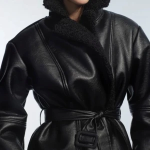 H&M viral jacka - Snygg svart teddyjacka i skinnimitation med bred krage i teddy och knytskärp i midjan. Jackan har oversized passform och långa ärmar, perfekt för kalla dagar. Stilsäker och trendig look med coola detaljer. Inköpt förra hösten och är använd men finns inga tydliga tecken på användning. Säljs inte längre på hemsidan. 