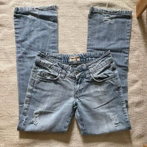 MDA by Madonna  - Vintage jeans från MDA by Madonna i ljusblå denim. De har en lätt sliten look med broderade bakfickor och fransade benslut. Jeansen är i storlek 28 och i väldigt fint skick – knappt använda. Pris går att diskuteras:) Midjemått: 37. Innerbenslängd: cirka 77,5 till 78 cm.