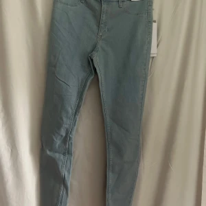 Nya ljusa jeans från H&M  - Säljer ett par helt nya och oanvända ljusblå skinny fit jeans med justerbar midja. Färgen är ljusare än bild 1-3, se bild 4. Klassisk femficksmodell med dragkedja och knapp framtill. Perfekta för dig som gillar en tight passform och stilren look.