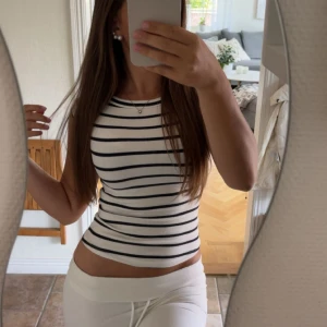 Randig vit och svart topp - Säljer en vit ribbad topp med svarta ränder från Zara. Materialet är stretchigt och bekvämt. Storlek s. Aldrig använd!