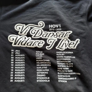 Svart Hov1 hoodie med turnétryck - Svart hoodie från Hov1 med turnétryck 'Vi Dansar Vidare I Livet' på ryggen och liten krona broderad framtill.  Nypris 700kr
