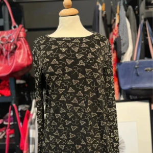 Svart tröja med unikt mönster - Svart långärmad tröja från Mac Scott med glittrigt mönster i guld och silver. Tröjan har en rak, lite loose passform och är dekorerad med glittrande detaljer över hela tyget. Perfekt för dig som gillar att sticka ut med coola detaljer. 