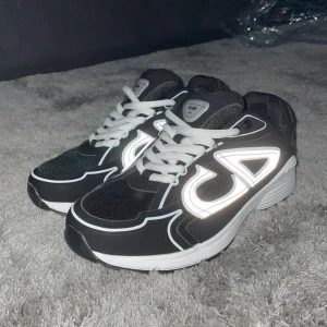 B30   - Säljer ett par B30 sneakers i svart med vita detaljer och reflekterande logga på sidorna. Skorna har en chunky vit och svart sula, mesh och syntetmaterial samt vita snören. Perfekta för dig som vill sticka ut med en lyxig och sportig vibe. Hör av dig till mig här på Plick vid övriga frågor💫👑