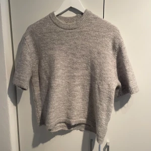 Grå stickad kortärmad tröja - Tröjan är endast använd en gång!Mysig grå stickad tröja med korta ärmar och rund hals. Tröjan har ribbade kanter vid hals, ärmslut och nederkant. Storlek S men passar även xs🤗