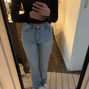 Ljusblå high waist jeans från Bershka - Säljer ett par ljusblå jeans från Bershka med hög midja och raka ben. Klassisk femficksmodell i denim med snygg tvätt och knappstängning framtill. Perfekta för dig som gillar en enkel och stilren look.