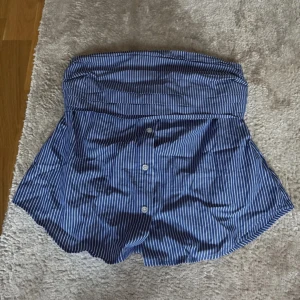 Blåvit randig bandeutopp från amisu - Säljer ett par blå vit randig topp med knappar framtill. Som en tubtopp i en skjort style 