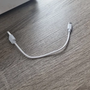 Champion Micro USB-laddkabel - Vit Micro USB-laddkabel från Champion, perfekt för laddning och dataöverföring till äldre Android-enheter och tillbehör. Kabeln är cirka 20 cm lång och i gott begagnat skick utan synliga skador eller slitage.