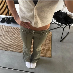 Lågmidjade gröna bootcut byxor - Snygga lågmidjade byxor i en olivgrön nyans med bootcut-ben, är slutsålda från hm. Byxorna har dekorativa fickor framtill, dubbla knappar och markerade .Jättefina till många outfits💗(andvänder bilder ifrån det förra jag köpte ifrån)