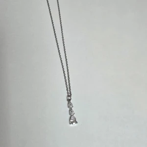 Silverhalsband med droppformade stenar s-stee 45 cml - Snyggt halsband i silverfärgat stål med tre droppformade glittriga stenar på rad. Kedjan är tunn och elegant, och hänget ger en stilren och modern vibe. Märkt med S-STEEL vilket visar att det är rostfritt stål. Perfekt för dig som gillar stilrena smycken med lite extra bling.