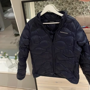 Peak performance - Säljer en mörkblå dunjacka från Peak Performance i storlek L(170cm). Jackan har quiltad design, dragkedja framtill och hög krage. Perfekt för kyliga dagar. Riktigt snygg till jeans eller träningsbyxor. Ej använd. Ny pris 1500kr