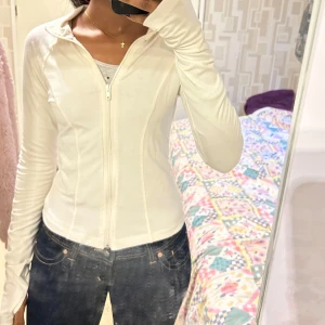 Vit ziptröja från Gina Tricot - Säljer en vit långärmad ziptröja från Gina Tricot i storlek S. Tröjan har dragkedja framtill, figurnära passform och hög krage. Aldrig använd endast testad