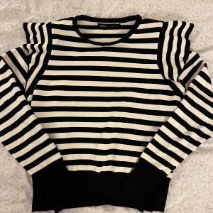 Randig svartvit tröja från ONLY - Säljer en svartvit randig tröja från ONLY med volanger på axlarna och långa ärmar. Tröjan har en klassisk rund halsringning och är tillverkad i ett mjukt stickat material. Perfekt för dig som gillar en trendig och stilren look🖤🤍