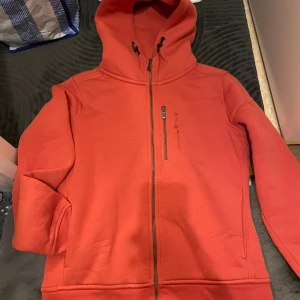 Sail Racing - En gosig fin hoodie perfekt för den kalla vintern. Den är varm i sig. Har använt den max 1-2 gånger. Upptäckte nu när jag skulle ta bild att det har blivit hål i vänstra armen 😖 se på bild.