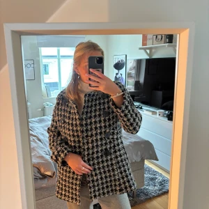 Rutig kappa från Designers Remix - Säljer en svart och vit rutig kappa från Designers Remix Collection i storlek L. Jackan har en snygg dubbelknäppning med stora knappar och ger en cool och trendig look. Den är liten i storleken, är mer som en stor S/liten M. Nypris ca 6 000kr.