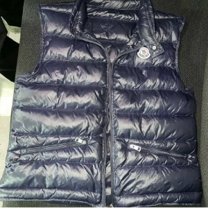 Mörkblå dunväst från Moncler - Snygg mörkblå dunväst från Moncler med glansig finish och klassisk logga på bröstet. Västen har hög krage, två dragkedjefickor framtill och quiltad design. Perfekt för lager-på-lager och streetstyle. Men dragkedjan funkar inte