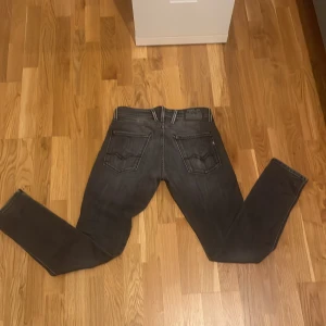 Replay Anbass svarta jeans, slim fit - Snygga svarta Replay Anbass jeans i slim fit med klassisk femficksdesign och diskreta slitningar. Jeansen har raka ben och är tillverkade i stretchigt denim för extra komfort. Perfekta för dig som gillar en modern och stilren look.