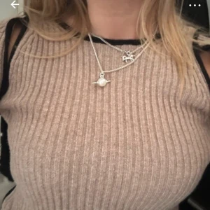 Beige ribbad långärmad tröja - Säljer en beige ribbad långärmad tröja med coola cut out-detaljer vid axlarna. Tröjan är figurnära och har svarta kanter som ger en snygg kontrast. Perfekt för dig som vill ha en trendig och unik look.