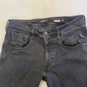 Replay Anbass svarta jeans, stl 32/34 - Svarta Replay Anbass jeans med klassisk femficksdesign och snygga detaljer på bakfickan. Jeansen har en smal passform och är tillverkade i stretchigt bomullsmaterial för extra komfort. Perfekta för dig som gillar en stilren look. Näst intill nyskick!                                                                   !!Om pris inte passar kom med bud!!