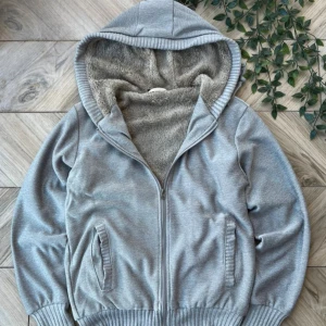 Grå hoodie med fluffigt foder - Mysig grå hoodie med dragkedja och fluffigt, mjukt foder på insidan och i huvan. Toppskick en skada. Storlek S. Fraktar samma dag!