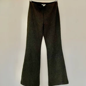 Svarta glittriga bootcut byxor - Byxor med svart bas och diskret guldglitter. Materialet är stretchigt och bekvämt. 