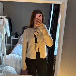 Beige stickad kofta - Säljer en beige stickad kofta med två snygga knyt framtill. Koftan har långärmade ärmar och en mjuk, ribbad struktur som gör den extra skön. ❤️