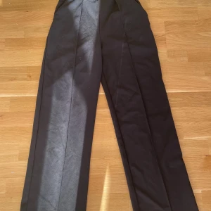 Svarta kostymbyxor från H&M XS - Svarta kostymbyxor från H&M i storlek XS. Byxorna har pressveck framtill och en klassisk rak passform med hög midja. Materialet är en blandning av polyester och elastan som ger en snygg och bekväm känsla. Perfekta för en clean och stilren look.