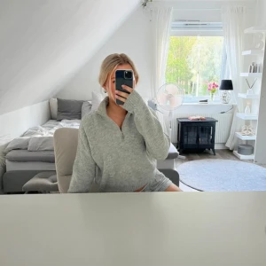 Grå stickad half zip tröja - Mysig grå stickad tröja med half zip och hög krage. Tröjan har en loose passform och långa ärmar