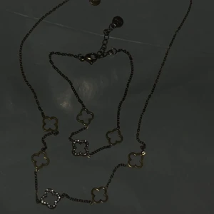Guldpläterat rostfrittstål halsband och armband  🍀  - Snyggt halsband och armband i guldpläterat rostfrittstål med flera fyrklöverformade länkar. Några av klöverhänget är dekorerade med små glittrande stenar för extra bling. Perfekt för dig som gillar detaljer och vill sticka ut lite extra.