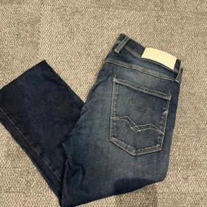 Replay Anbass slim jeans mörkblå - Snygga mörkblå Replay Anbass jeans i slim fit med klassisk femficksdesign och coola kontrastsömmar på bakfickan. Jeansen är tillverkade i stretchigt denim för extra komfort och har en stilren look som passar perfekt till sneakers eller boots.