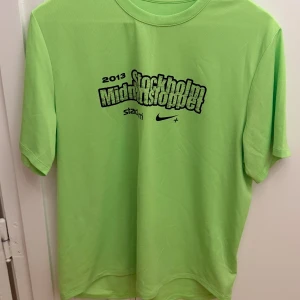 Nike Dri-Fit Stockholm Midnattsloppet T-shirt - Grön Nike Dri-Fit t-shirt från Stockholm Midnattsloppet 2013. Tillverkad i 100% polyester med tryck fram och bak. Perfekt för träning med lätt och ventilerande material. Klassisk passform och korta ärmar. Storlek L.