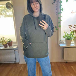 Grön hoodie - Skogs-grön hoodie. Ficka på magen. Mått: Arm - 64 cm, Axelbredd - 55 cm, Längd - 66 cm. (Säljer denna åt min sambo som är 194 cm lång och har normalt L/XL) (2a bilden är tyvärr tagen i väldigt dåligt ljus, 1a bilden representerar färgen bra)