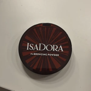 IsaDora Bronzing Powder Beach Tan - IsaDora The Bronzing Powder i nyansen 49 Beach Tan. . Ger en solkysst look med en varm, gyllenbrun ton. Vegansk, doftfri och kliniskt testad. Perfekt för att framhäva ansiktets konturer. Testad 