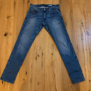 Blå Replay jeans med raka ben - Snygga blå jeans från Replay med klassisk femficksdesign och raka ben. Jeansen har diskreta slitningar och snygga detaljer på bakfickorna samt Replay-logga på bakre linningen. Perfekta för en avslappnad och trendig look. Aldrig använt