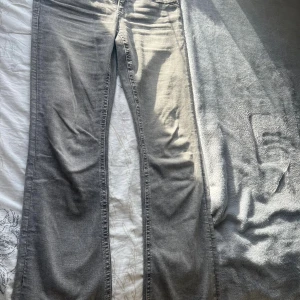 Grå low waist bootcut jeans från Gina Tricot storlek 170  - Snygga grå jeans från Gina Tricot med bootcut passform. Modellen på bilden är 167 cm lång och de sitter perfekt i längden. Jeansen har coola detaljer med grovstickade sömmar på bakfickorna och klassisk femficksdesign. Tillverkade i mjuk bomullsdenim med dragkedja och knapp framtill. Använda fåtal gånger men i nytt skick.