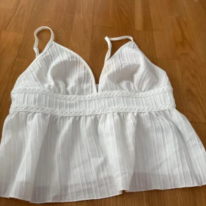 Vit linnetopp från SHEIN med spetsdetaljer - Superfin vit linnetopp från SHEIN med tunna axelband och v-ringning. Toppen har en flowy passform nedtill och dekorativa spetsdetaljer vid midjan. Perfekt för varma dagar och ger en fräsch look till din outfit.