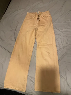 Beige wide jeans från 157 Boulevard - Snygga beige jeans från Lager 157  i storlek 36/ S Modellen har hög midja, raka ben med wide fit och klassisk femficksdesign. Materialet är robust denim med dragkedja och knapp framtill. Perfekt för dig som gillar avslappnad och trendig stil.